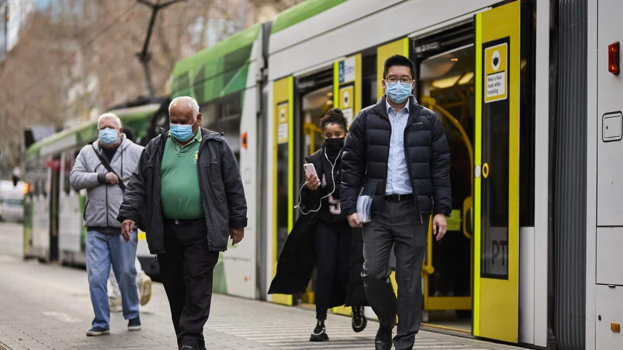 People wearing face masks getting off a tram