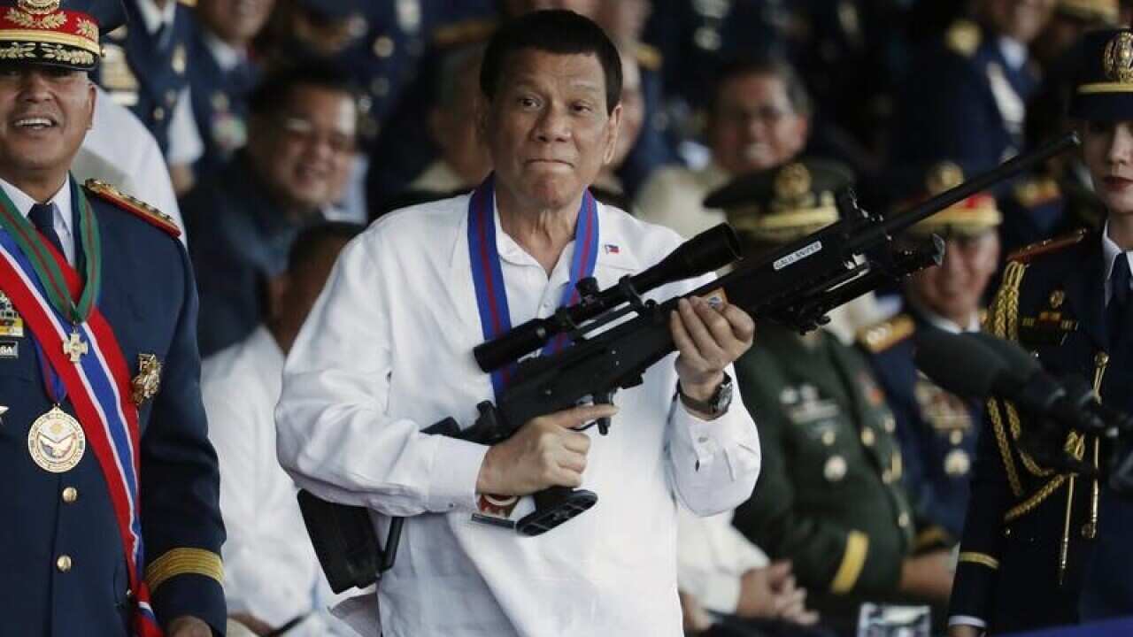 Filipino President Rodrigo Duterte holds a rifle at a police ceremony.