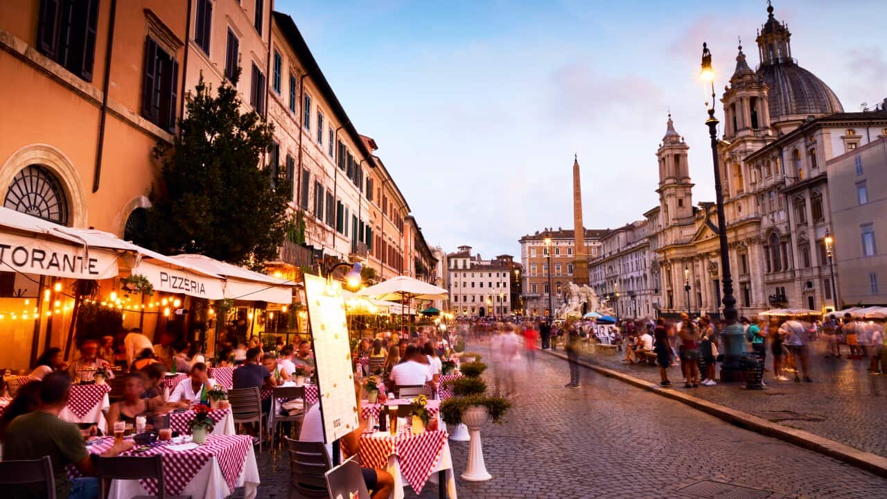 People dining outside in Piazza Navona in Rome at dusk