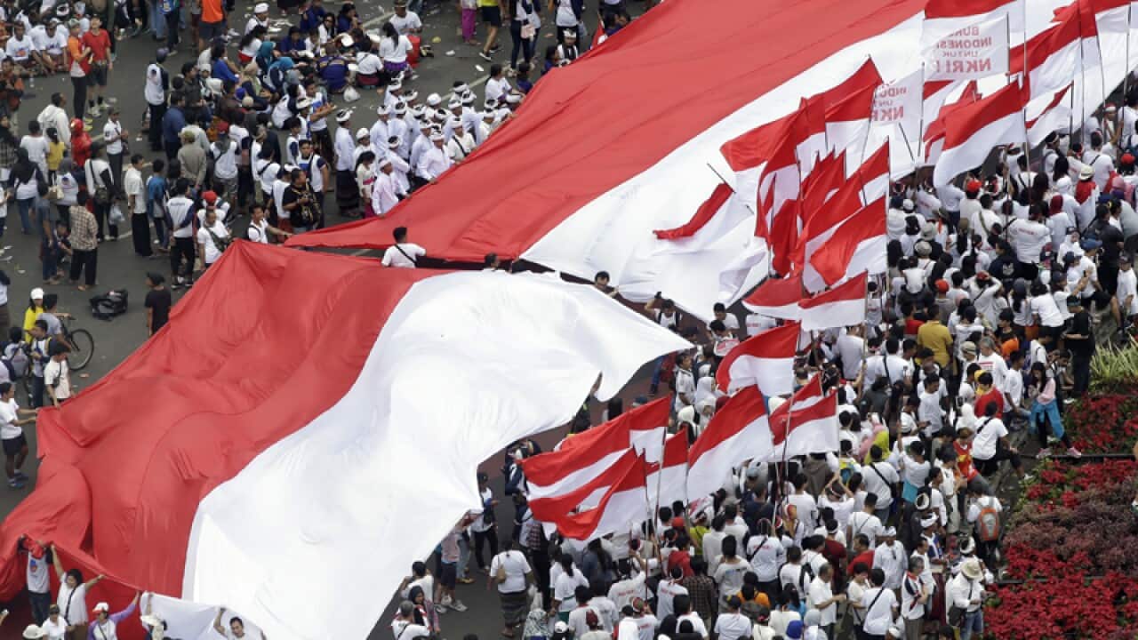 Indonesians display a large national flag during a rally in Jakarta