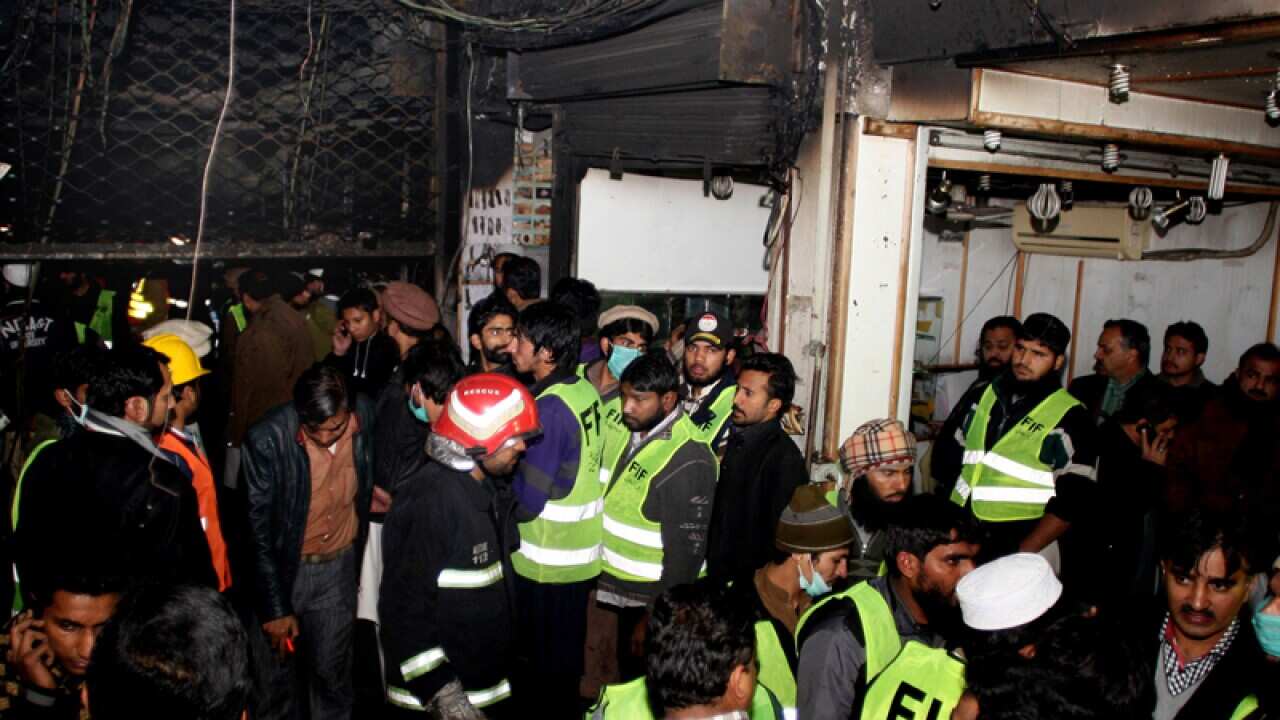 People gather at the entrance of a damaged building in Lahore