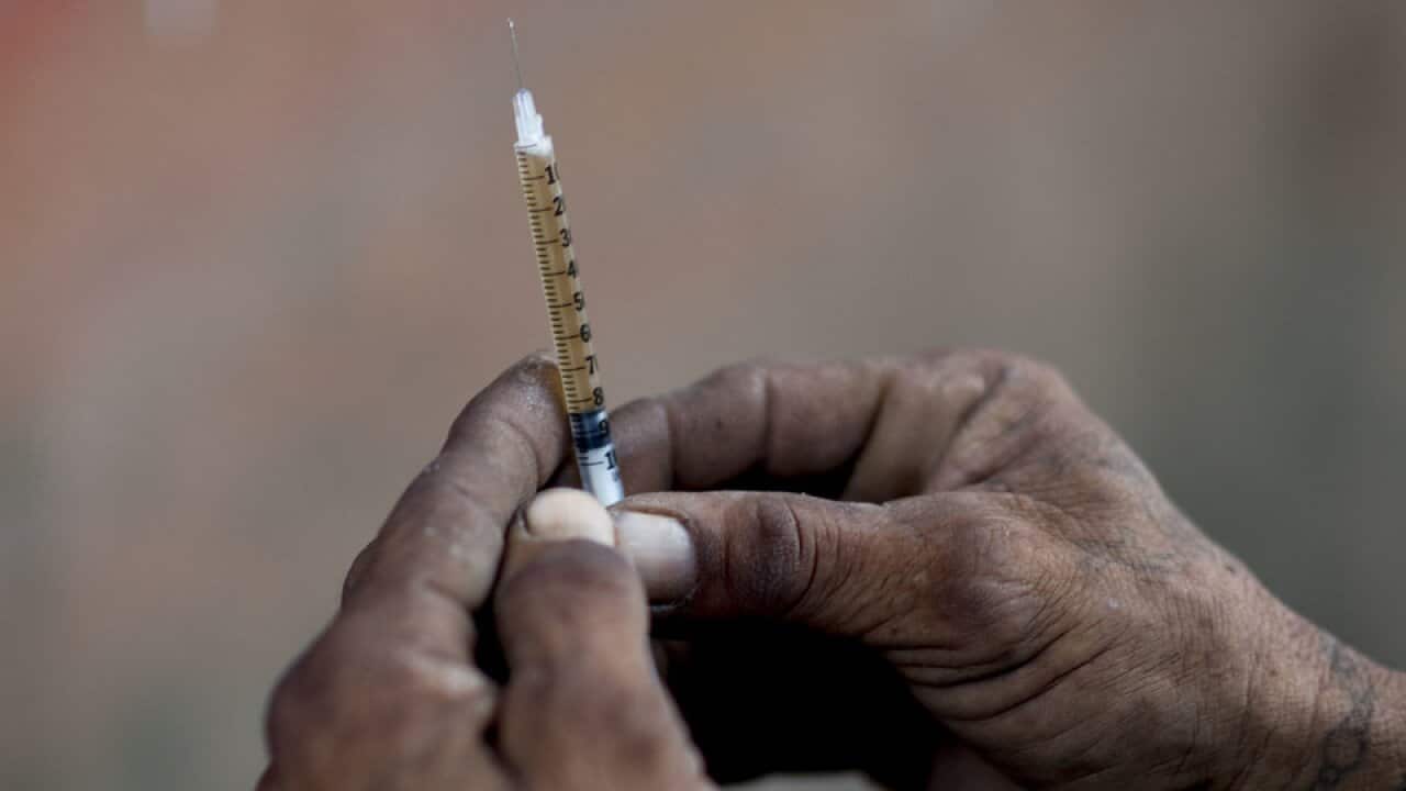 A heroin addict prepares a dose