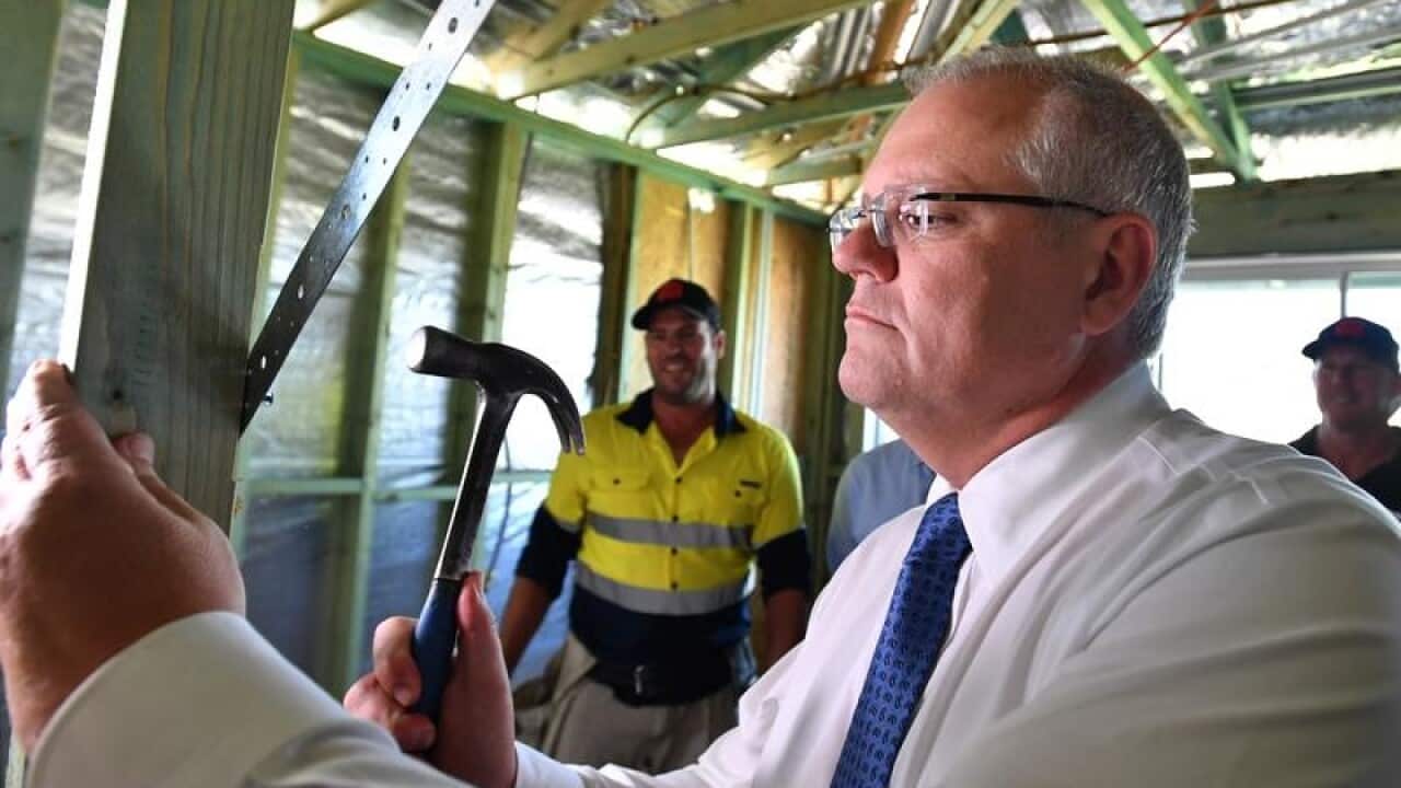 Prime Minister Scott Morrison hammers a nail at a building site