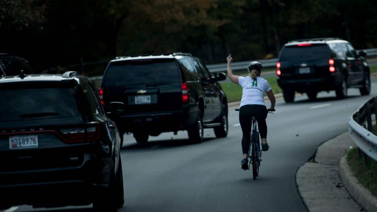Juli Briskman gestures with her middle finger as a motorcade with US President Donald Trump departs Trump National Golf Course October 28, 2017