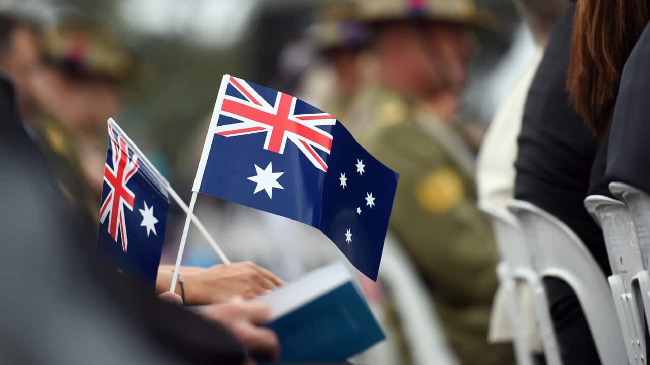 Memmbers of the public hold flags at an Australia Day Citizenship