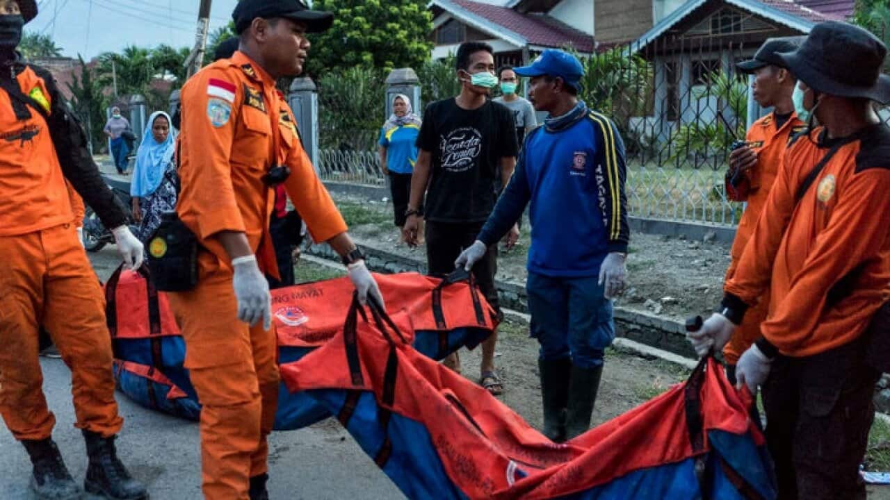 The bodies of people killed in last week's earthquake and tsunami are carried from the Balaroa neighborhood of Palu.