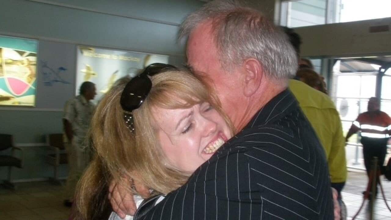 a man and woman hugging passionately at the airport the woman has a very expressive look on her face and their hug tightly