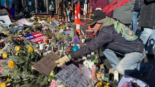A man places a sign that says "In remembrance of my angel" at a memorial set up at the location where Veterans Affairs nurse Alex Pretti was shot by U.S. federal agents, in Minneapolis,