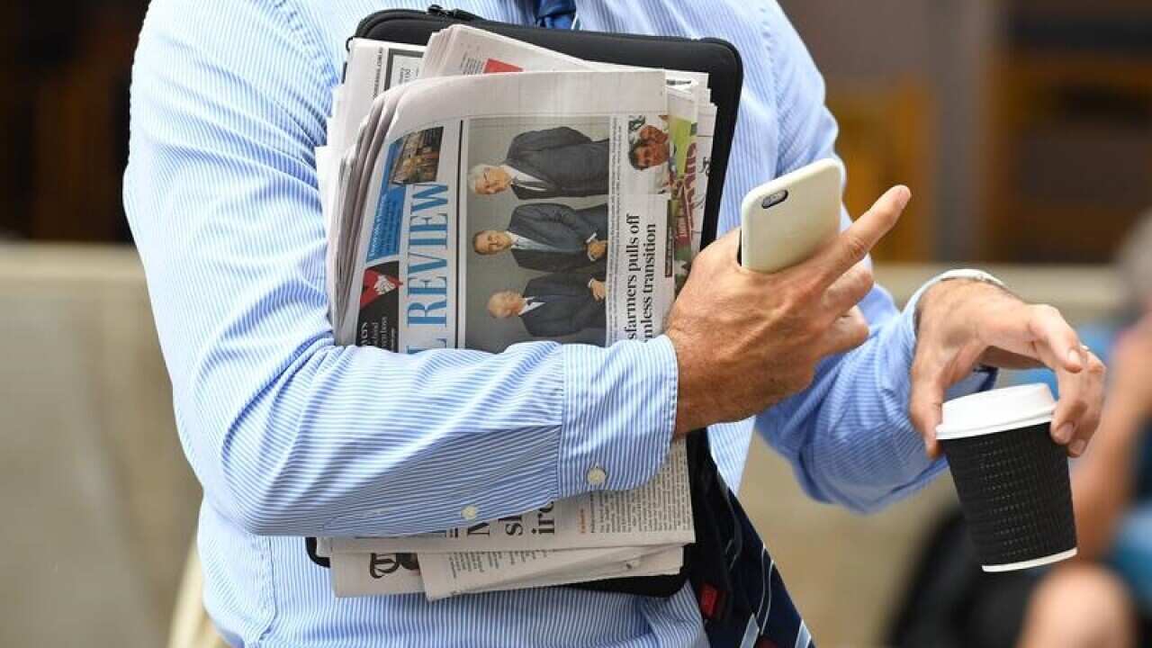 A business man holds a newspaper and coffee