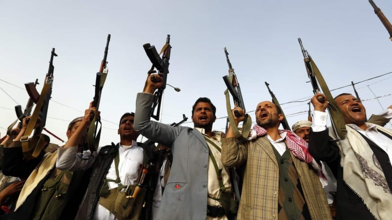 Armed Houthi supporters raise their guns aloft in Yemen