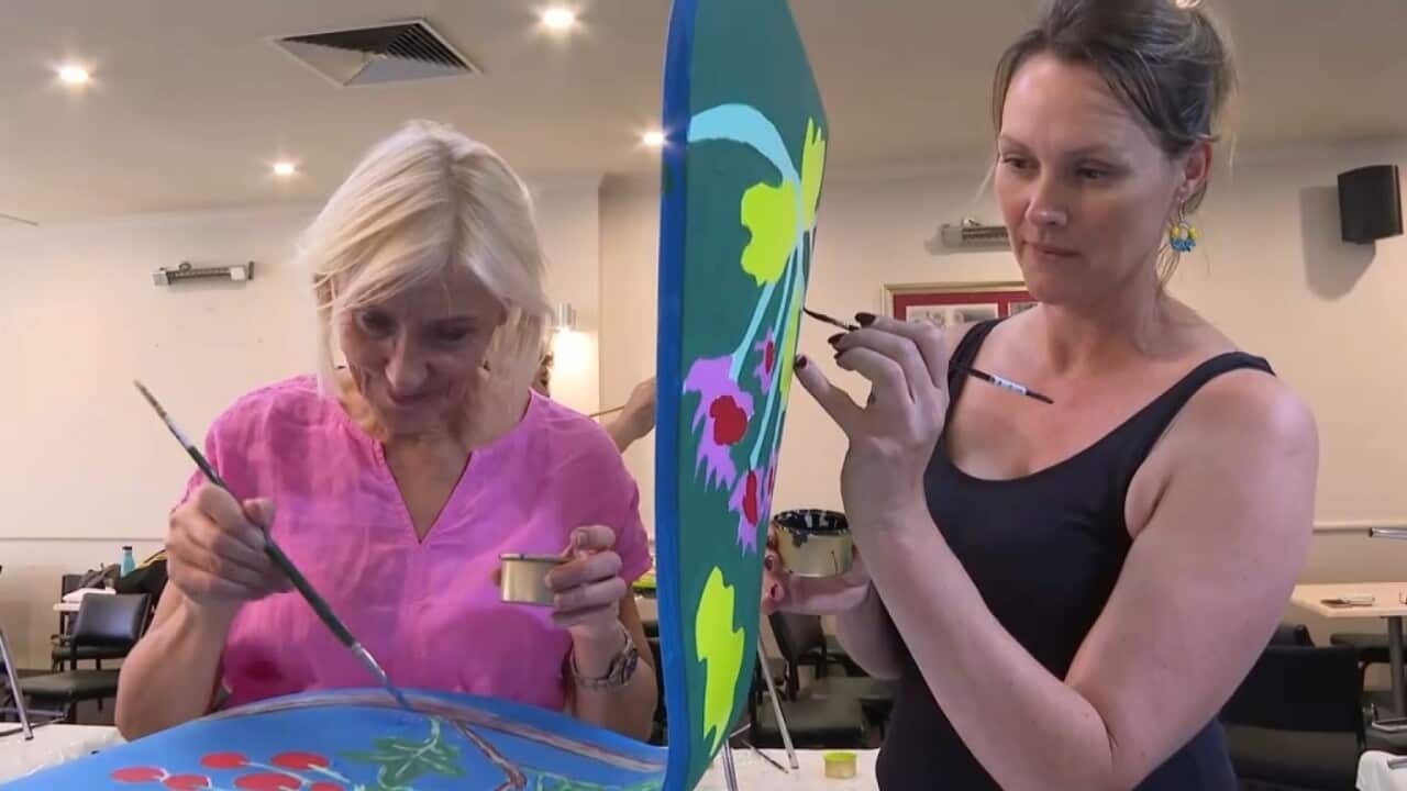 Displaced Ukrainian woman Nataliia and friend painting chairs at Kozba cafe.