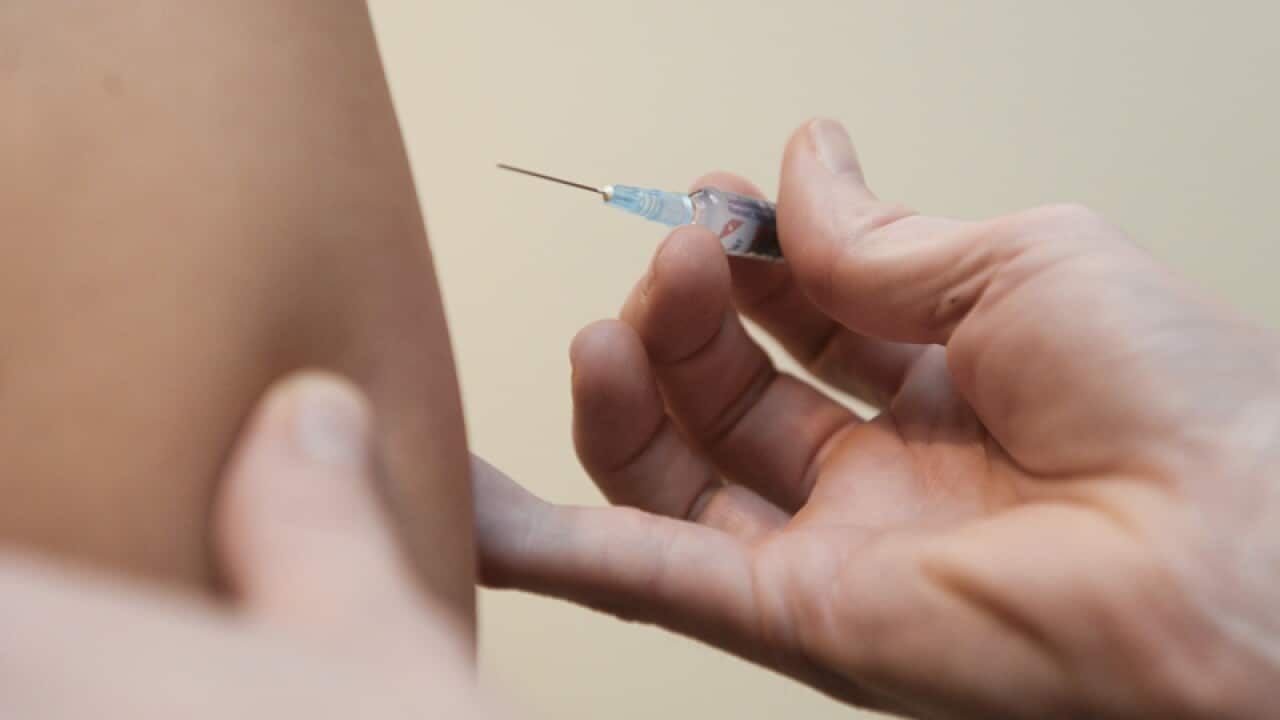 A doctor injects a vaccine at a clinic