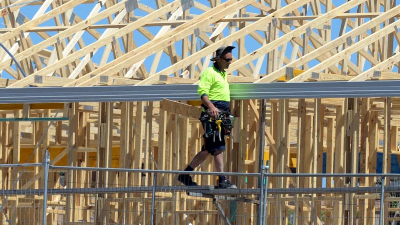 A carpenter works on a home under construction