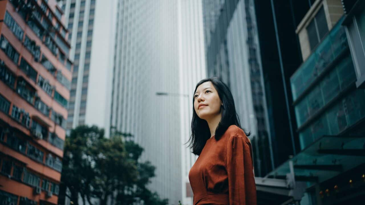 Low angle portrait of confidence young woman standing against highrise city buildings in city