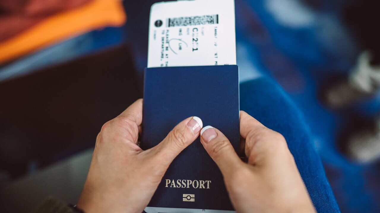 A woman holding a passport and a boarding pass.