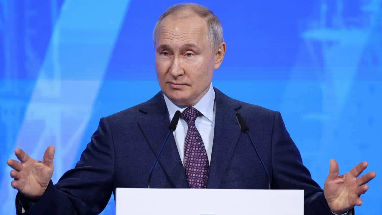 A man in a suit speaks in front of a mic.