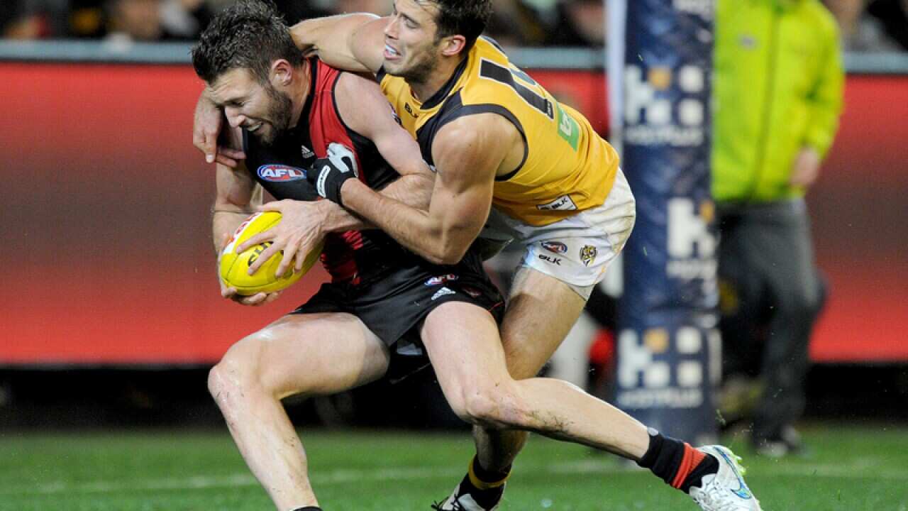 Essendon's Cale Hooker is tackled by Richmond's Alex Rance