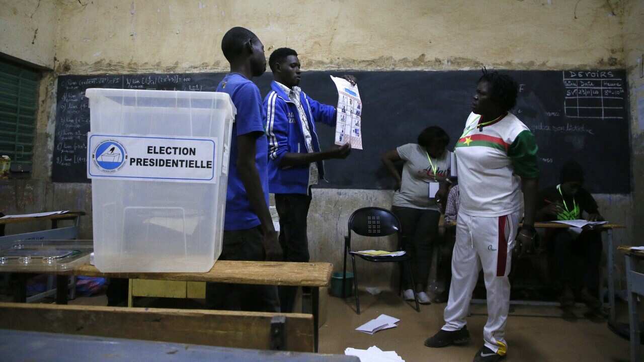 A Burkina Faso electoral official holds up a ballot as counting starts in the first round of the presidential election