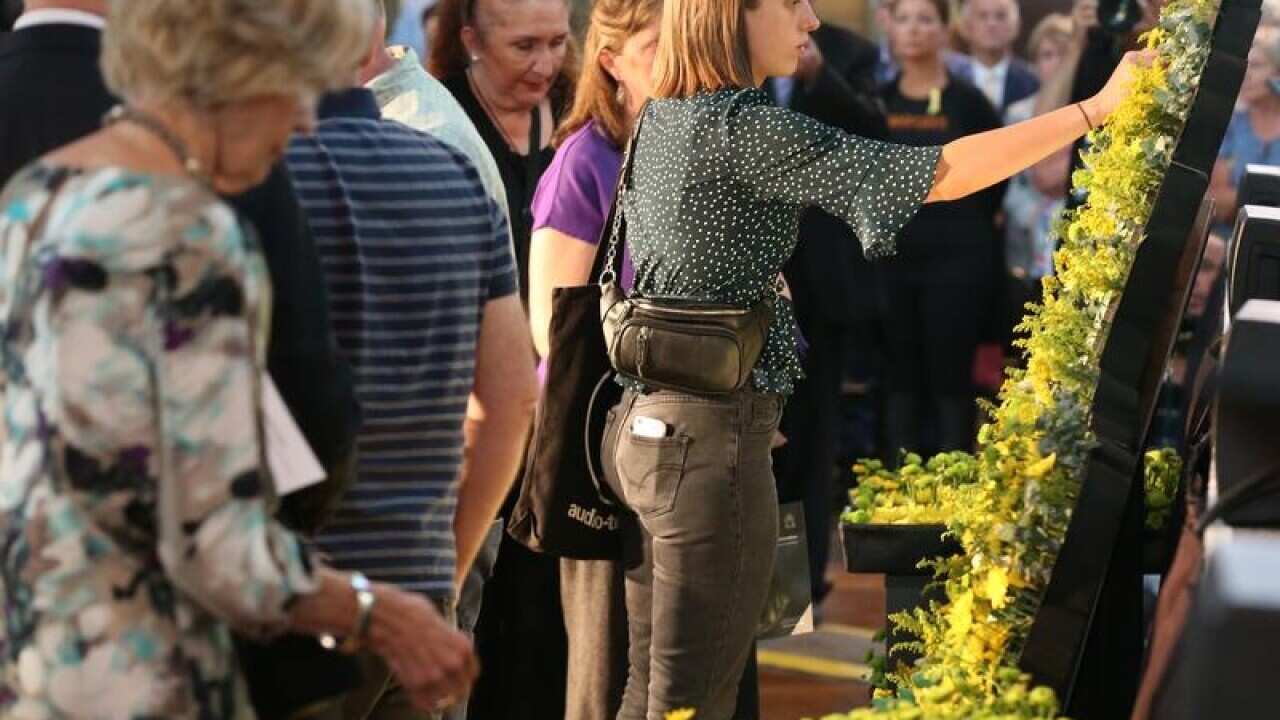 People place flowers by a model of Victoria.