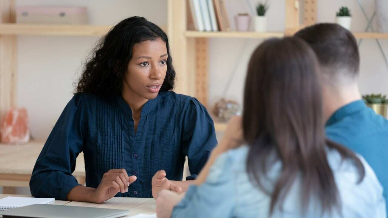 Female Real Estate Agent consult young couple at office meeting