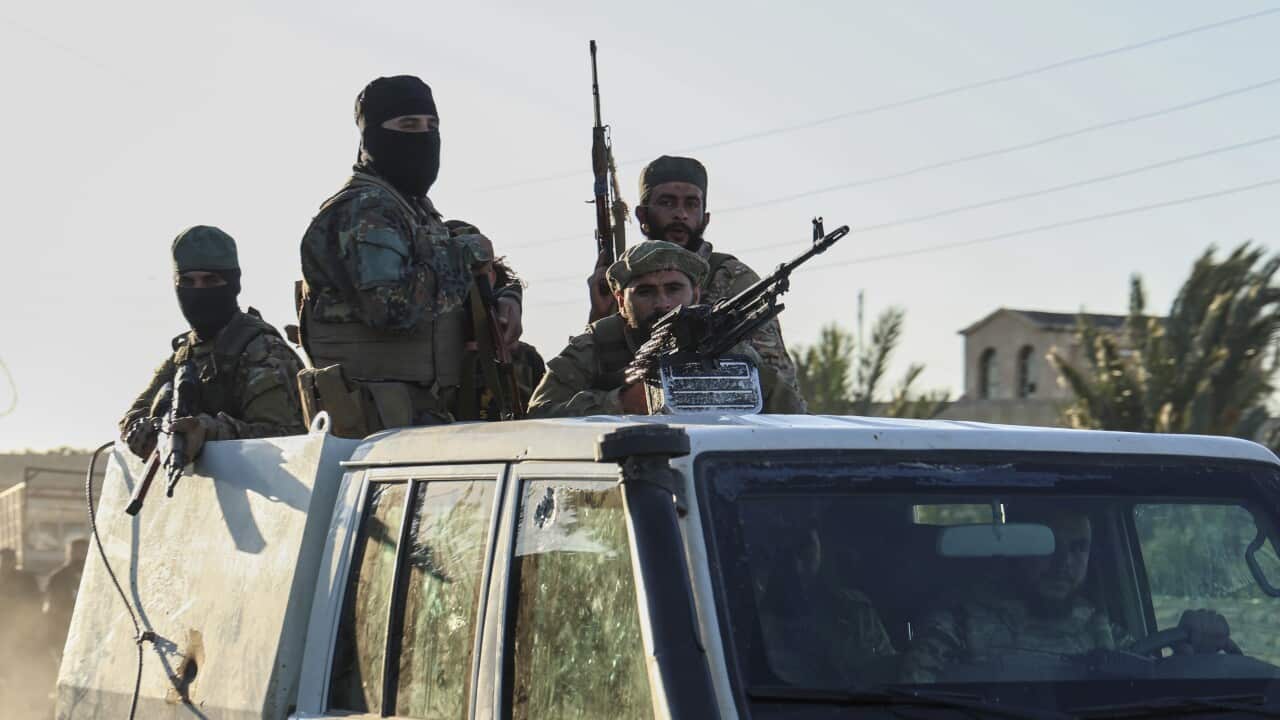 Security forces carrying weapons atop a jeep.
