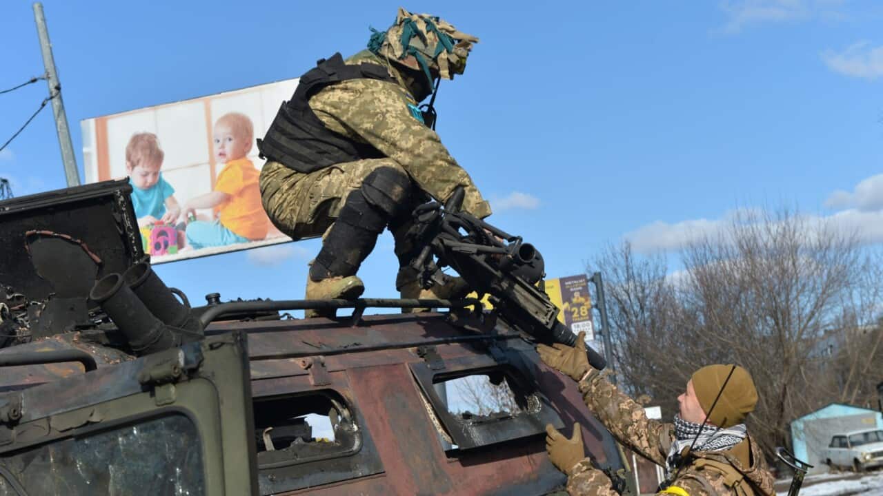 TOPSHOT - An Ukrainian Territorial Defence fighter takes the automatic grenade launcher from a destroyed Russian infantry mobility vehicle GAZ Tigr after the fight in Kharkiv on February 27, 2022. -