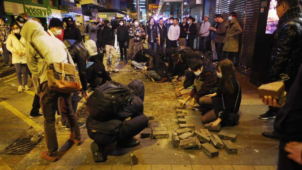 Protesters collect bricks from a pathway during clashes with