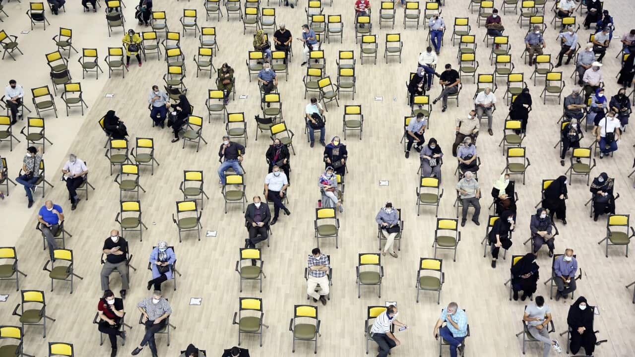 People wait to receive a COVID-19 vaccine in a vaccination station at the Iran Mall shopping centre, in Tehran.