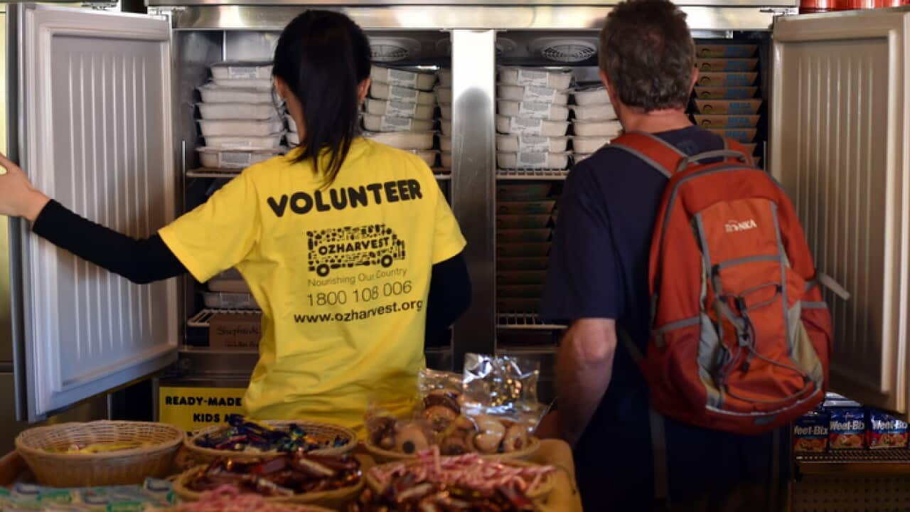 A volunteer helping a customer in the frozen food section of OzHarvest Market, a recycled food supermarket, in Sydney