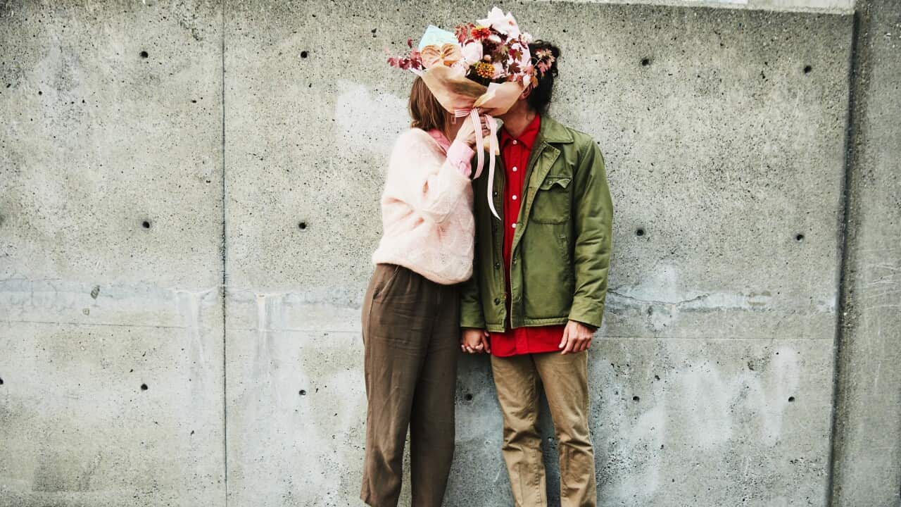 Portrait of couple kissing while hidden behind bouquet of flowers
