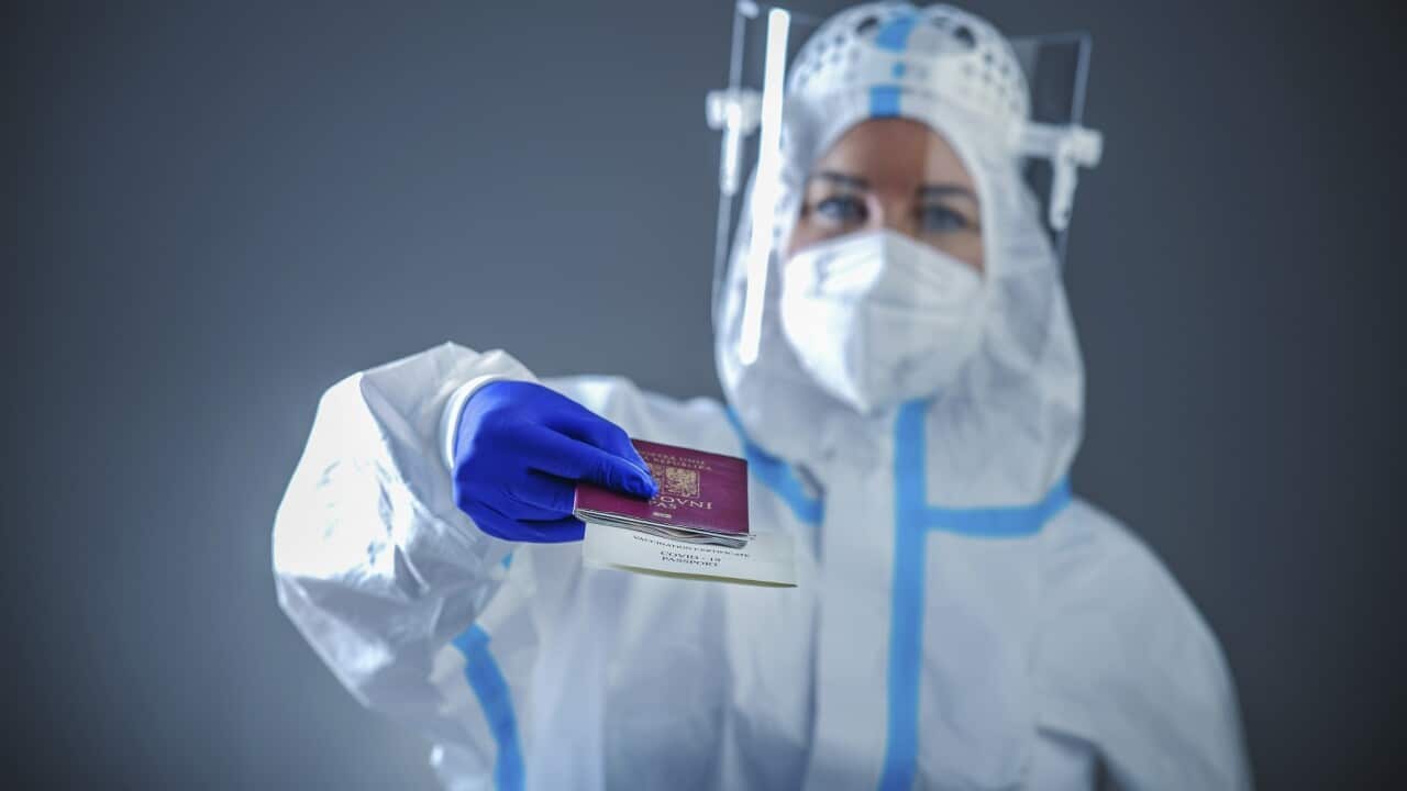 Doctor or medic in a protective suit holding a passport of the Czech Republic with a printed certificate of infectivity on Covid - 19, QR code, Covid passport Photo/Vojtech Vlk (CTK via AP Images)