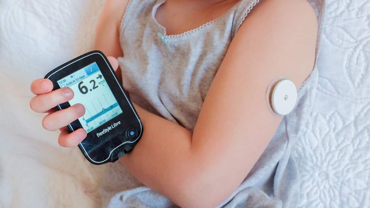 A child checks her blood sugar by scanning a glucose sensor