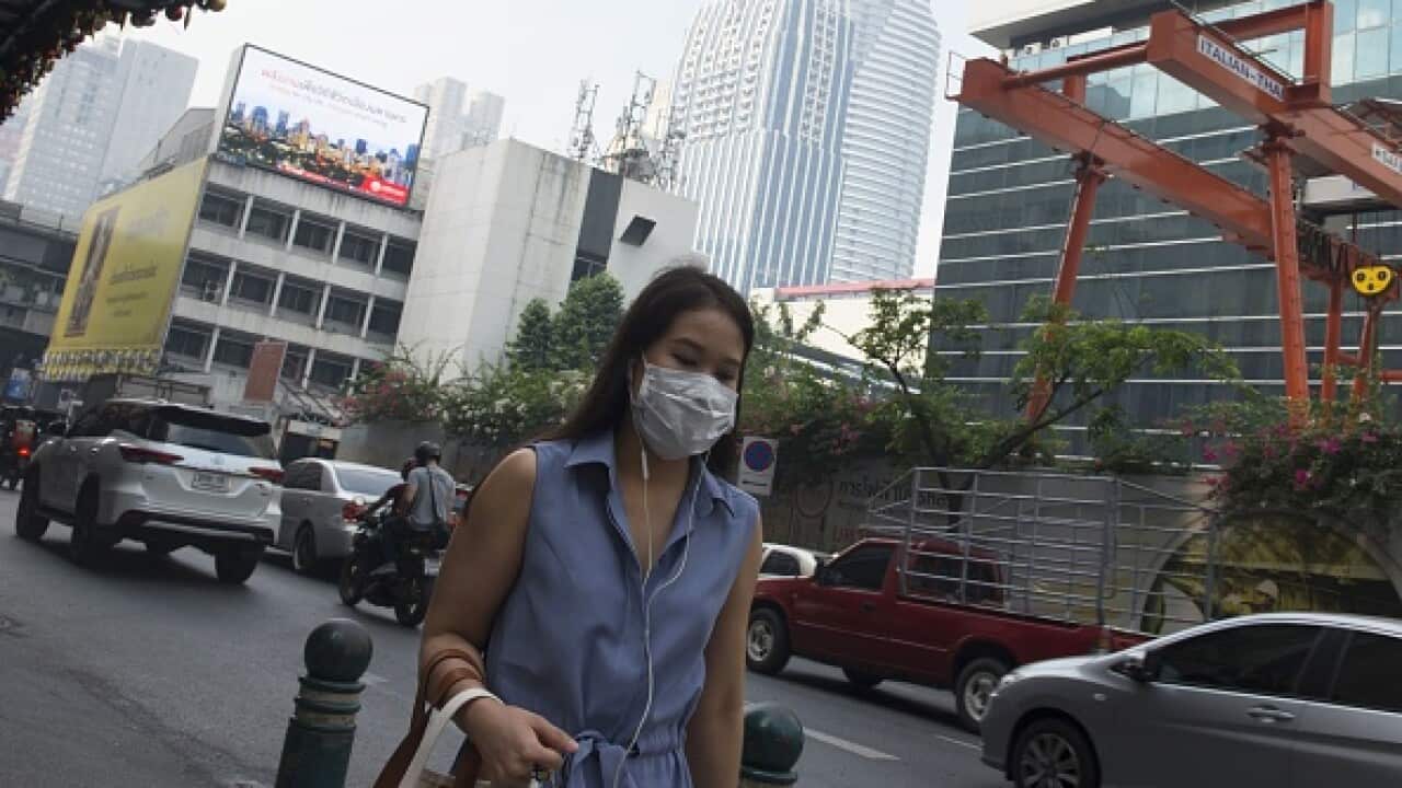 A woman wears a face mask on the way to work while smog blankets Bangkok.