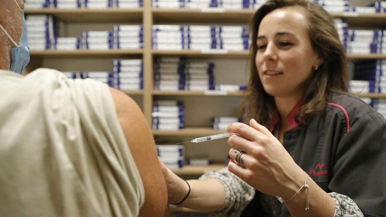 A pharmacist administers a COVID-19 vaccine.