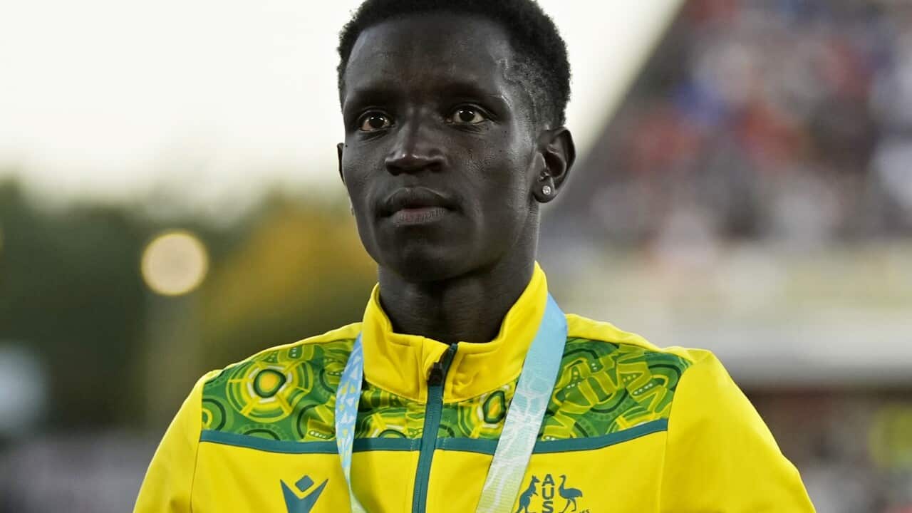 A man wearing a yellow tracksuit standing outside.