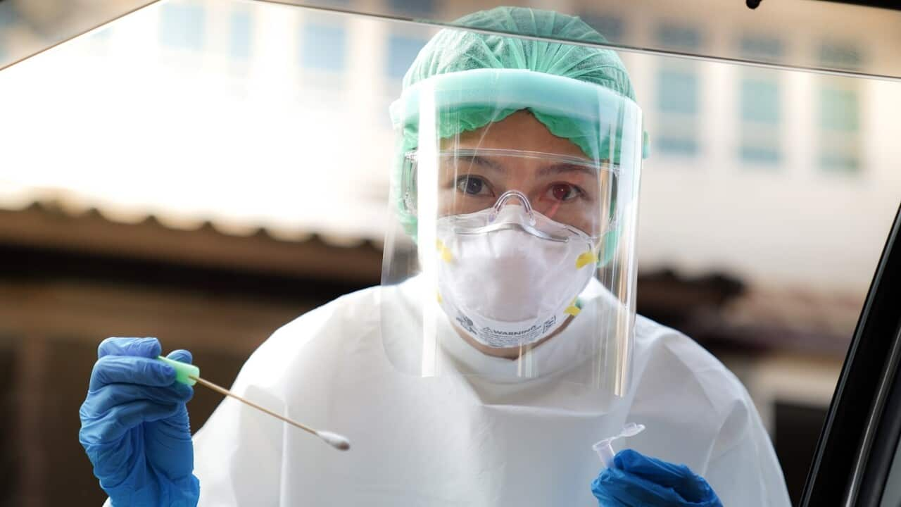 Portrait Of Doctor Wearing Protective Workwear Holding Medical Equipment Seen Through Car Window