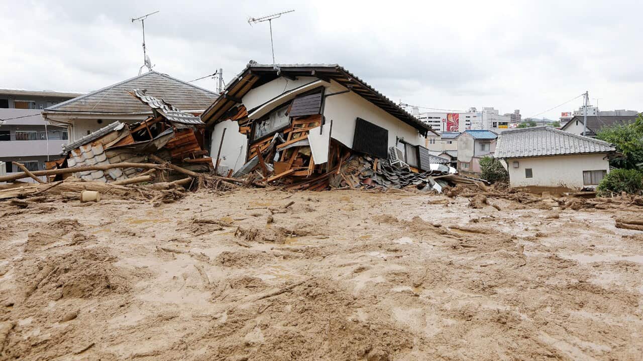 Collapsed houses sit surrounded in mud after a landslide hit the area caused by heavy rains in the city of Hiroshima, western Japan