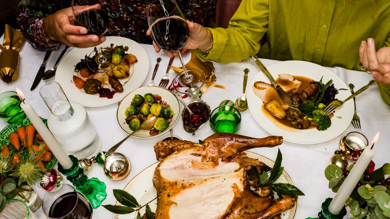 Close-up aerial view of people sitting at at table having a Christmas dinner, including roast chicken.