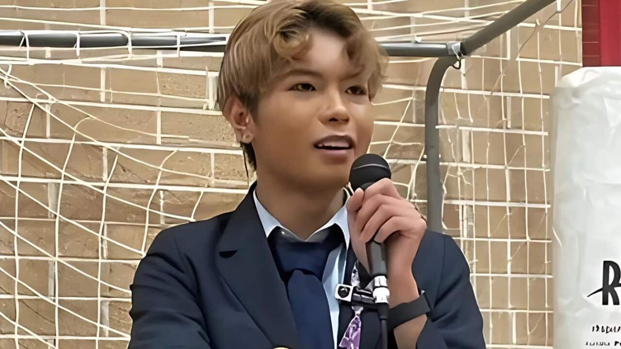 A student speaking into a microphone to an audience.