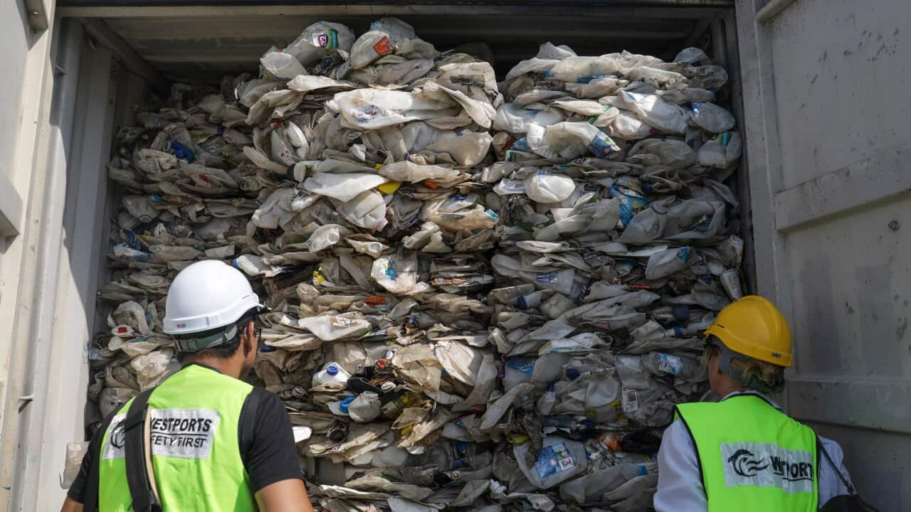 Members of the media look at plastic waste inside cargo containers before it is sent back to the country of origin.