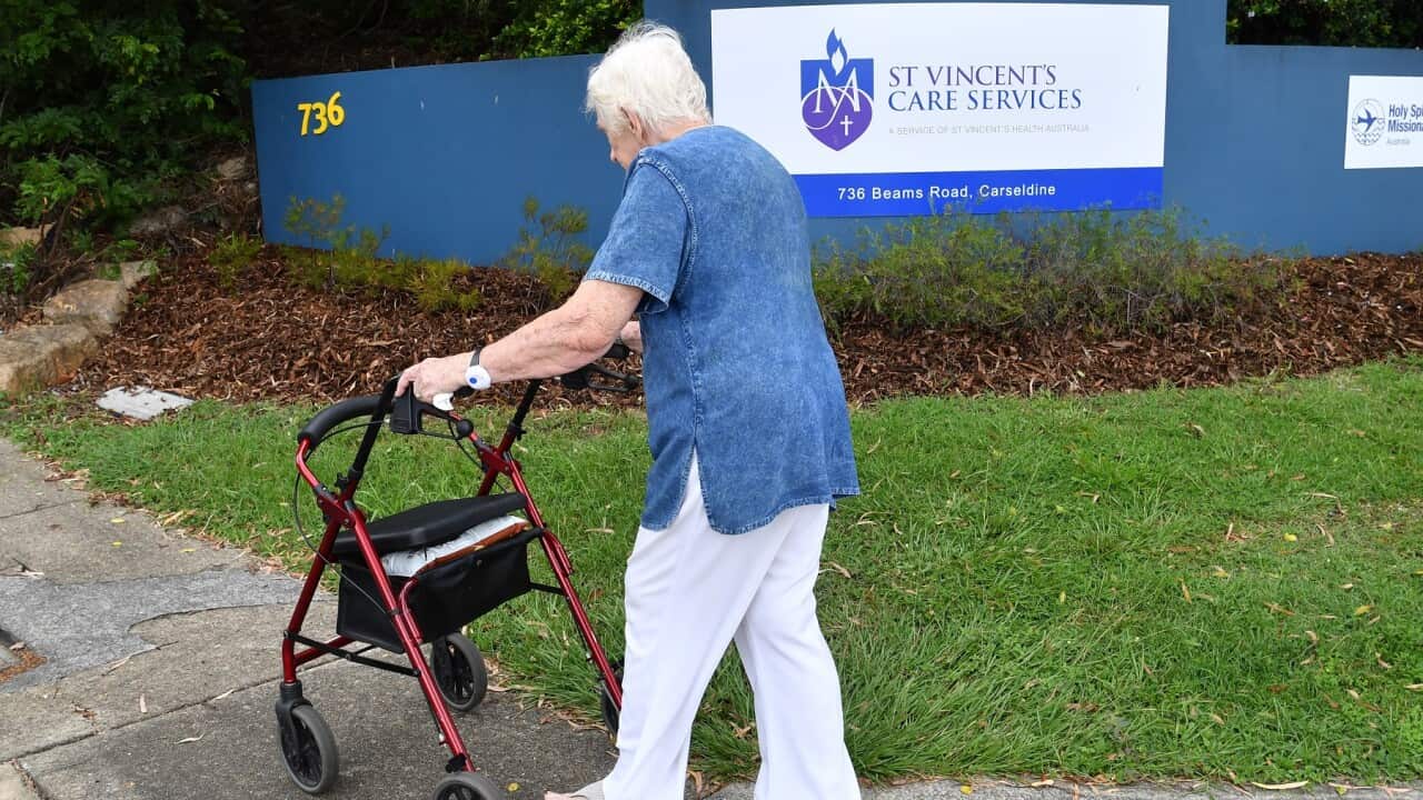 An elderly women is seen walking into the entry of the Holy Spirit Nursing Home, Carseldine in Brisbane.
