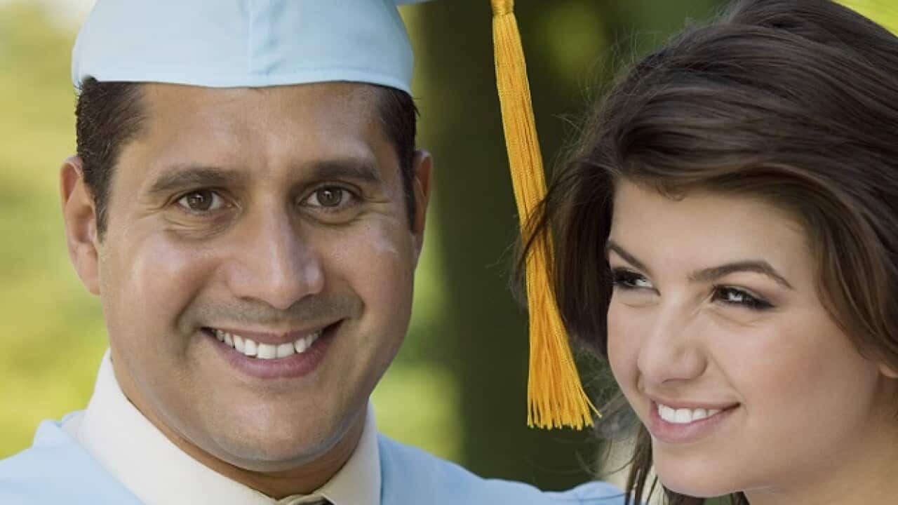Middle-aged graduate receiving present from daughter outdoors