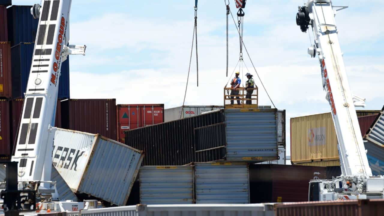Workers examine toppled shipping containers