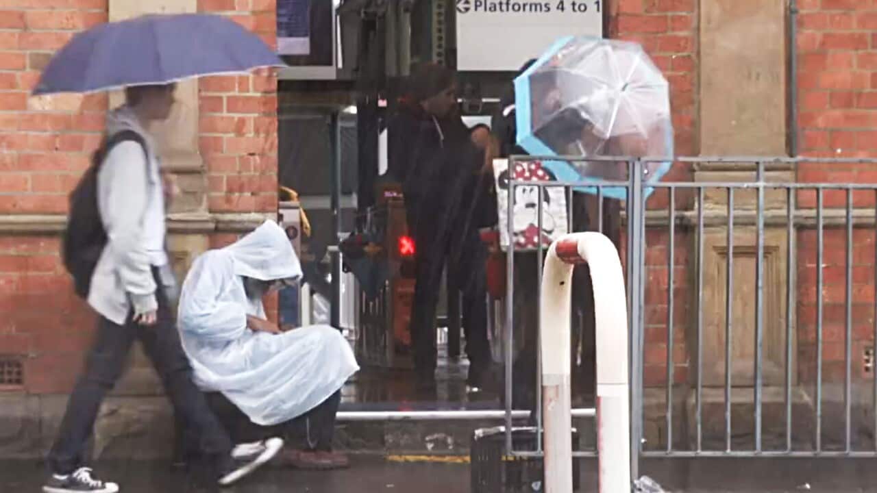 Man sits by Redfern station in the Sydney storm