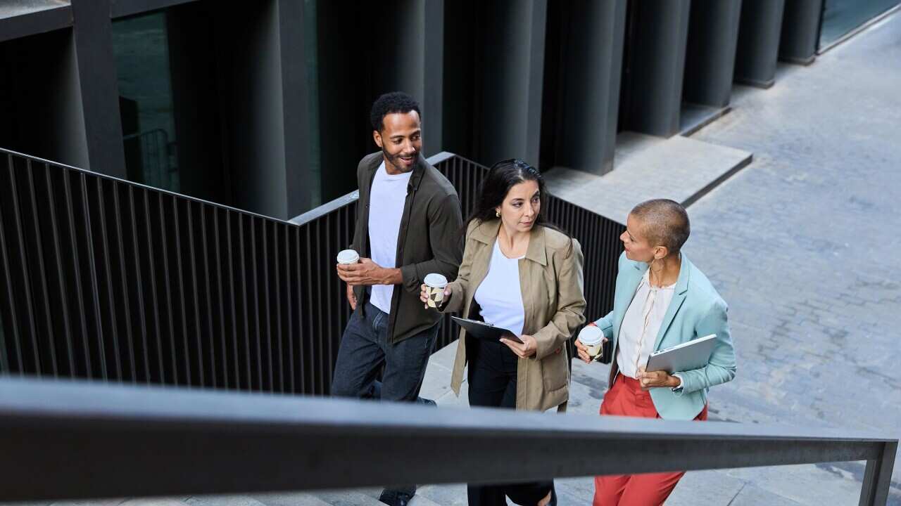 Three workers walking up stairs with a coffee in hand.