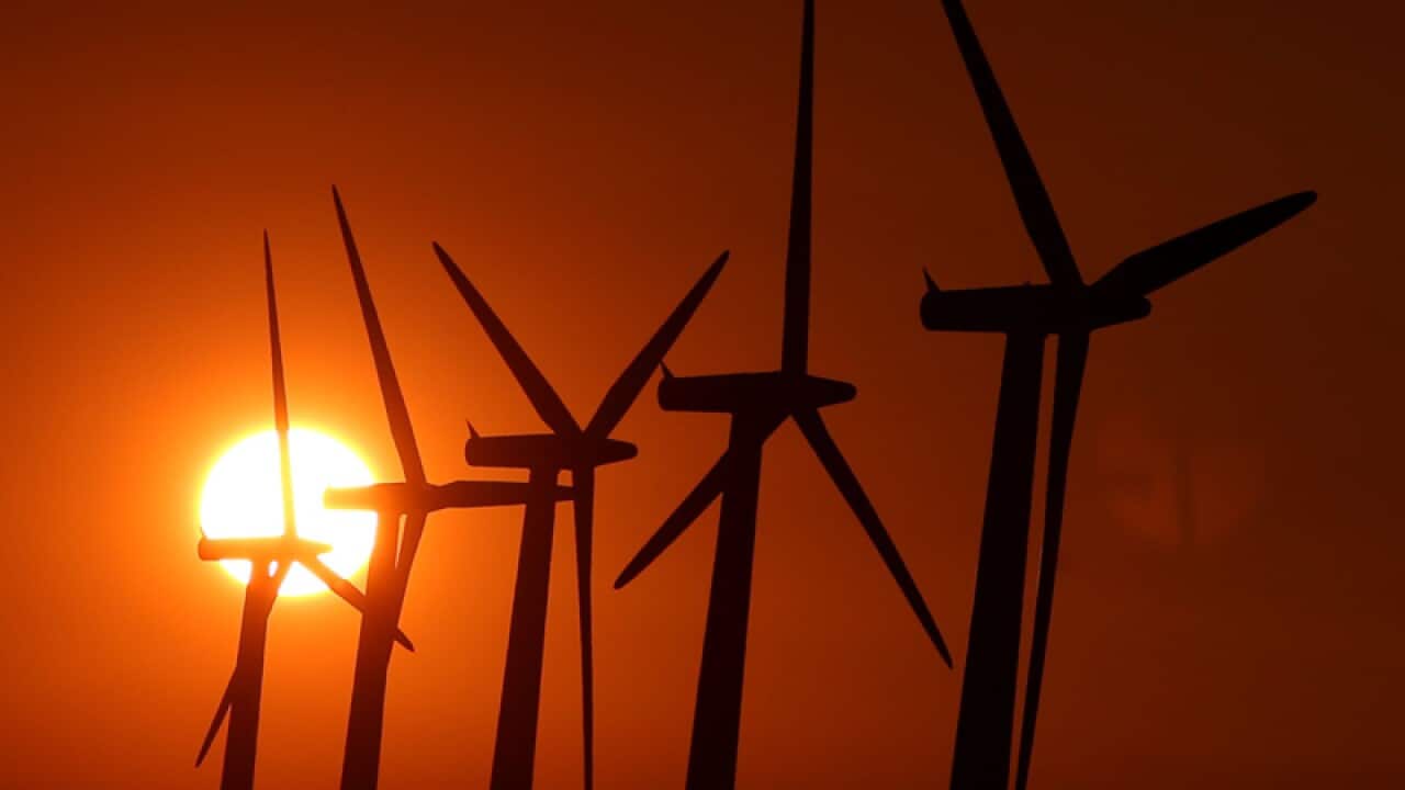 sun setting over wind turbines