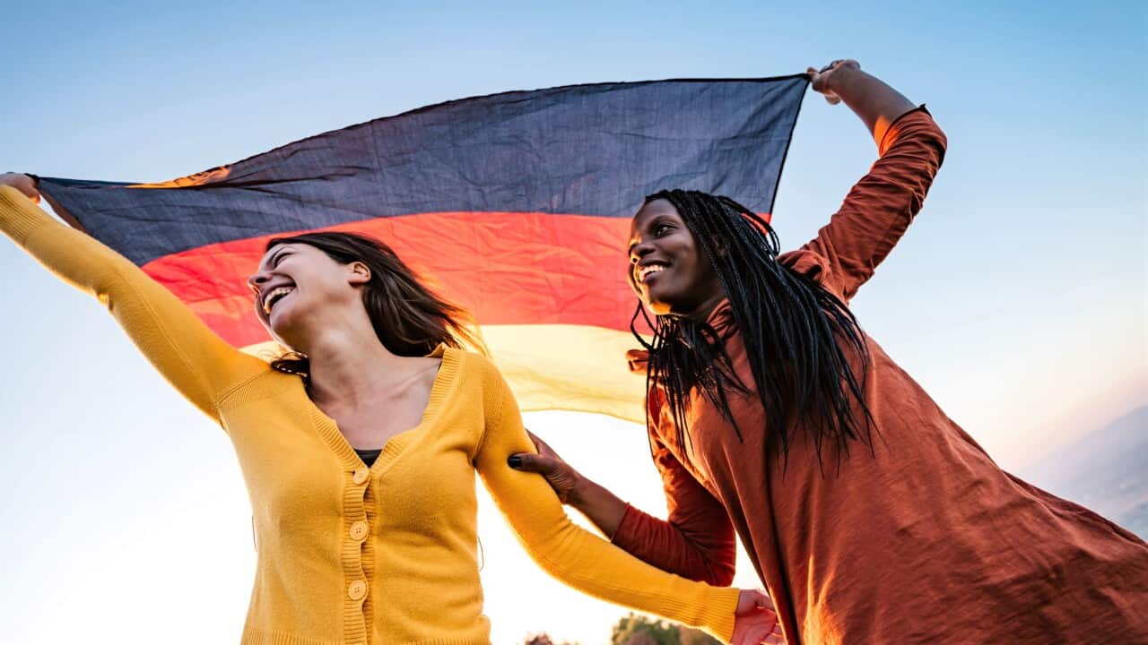 Two multi-ethnic women holding German flag