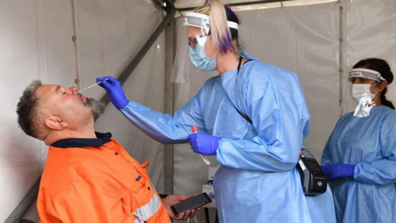 Truck driver Justin Stephens (left) is seen having a COVID-19 test performed by Sandy O'Brien (centre) from 4Cyte Pathology