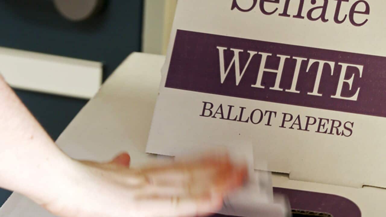 A voter drops a ballot at a polling booth