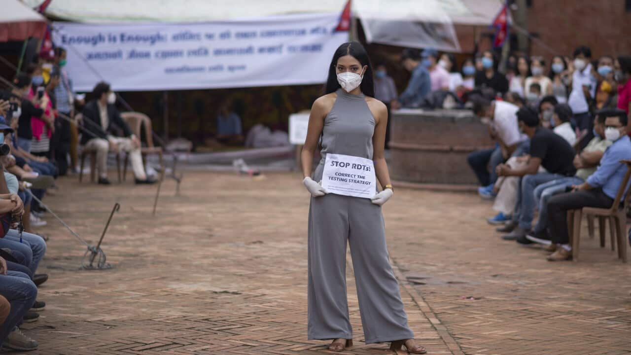 A model wearing a face mask with a placard catwalks during the protest in Kathmandu Nepal against what the protesters describe as government inaction in providing better covid-19 response.